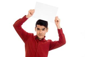 jovem modelo masculino bonito na camisa vermelha com cartaz vazio nas mãos, isolado no fundo branco foto