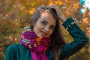 linda jovem em um cachecol quente mantém sua mão para o cabelo e close-up sorridente foto