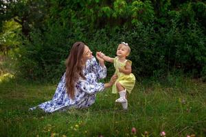 feliz jovem mãe brinca com sua filha no jardim verde foto