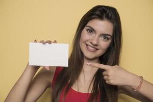 jovem mulher sorridente segurando uma folha de papel em branco para publicidade foto