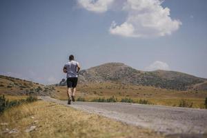 corredor de homem desportivo correndo no planalto da montanha no verão foto