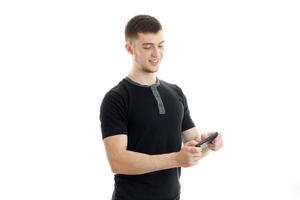cara jovem alegre em uma camiseta preta e inclui música no telefone foto