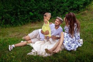 família alegre se divertindo no parque. pais com filha relaxando ao ar livre. foto