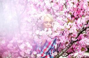 menina elegante em uma pilha de flores rosa florescendo foto