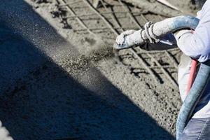 trabalhador da construção civil atirando concreto, concreto projetado ou gunite através da mangueira foto