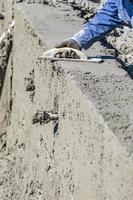 trabalhador da construção civil piscina trabalhando com flutuador de madeira em concreto molhado foto