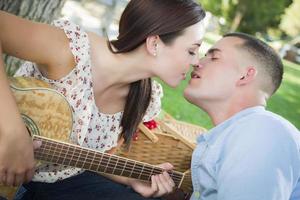 casal de raça mista com beijo de guitarra no parque foto