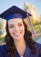 feliz graduando-se mulher de raça mista em boné e vestido foto