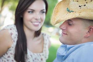 casal romântico de raça mista com chapéu de cowboy flertando no parque foto