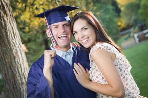 graduado masculino em boné e vestido e menina comemoram foto