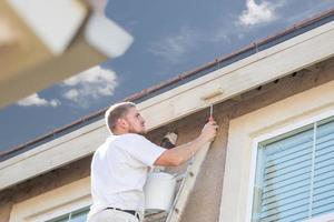 pintor profissional usando rolo pequeno para pintar a fachada da casa foto