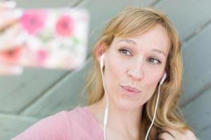 jovem adulta usando fones de ouvido tirando uma selfie com seu telefone inteligente. foto