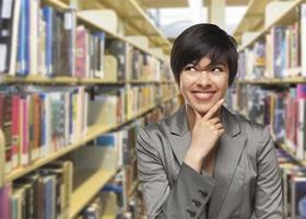 garota de raça mista olhando para o lado na biblioteca foto