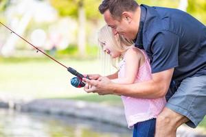 jovem caucasiano pai e filha se divertindo pescando no lago foto