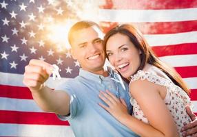 casal militar segurando as chaves de casa na frente da bandeira americana foto