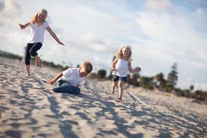 adorável irmão e irmãs se divertindo na praia foto