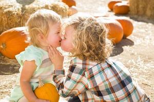 menino doce brinca com sua irmãzinha em um rancho rústico no canteiro de abóboras. foto
