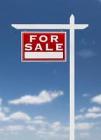 frente esquerda para venda sinal imobiliário em um céu azul com nuvens. foto