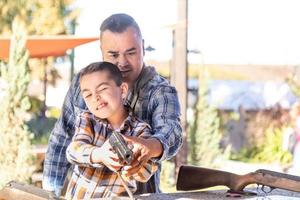 pai e filho de raça mista no campo de tiro do parque de diversões foto