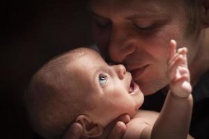 jovem pai segurando seu bebê recém-nascido mestiço foto