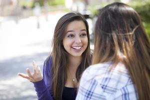 mulher jovem e expressiva de raça mista sentada e conversando com a namorada foto