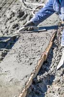 trabalhador da construção civil piscina trabalhando com flutuador de madeira em concreto molhado foto