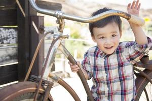 menino de raça mista se divertindo na bicicleta foto