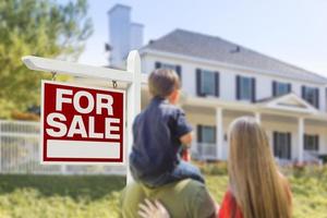 família de frente para venda sinal imobiliário e casa foto