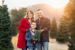 família de raça mista ao ar livre na fazenda de árvores de natal foto