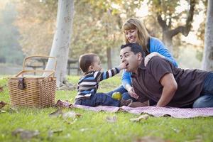 feliz família étnica de raça mista fazendo piquenique no parque foto