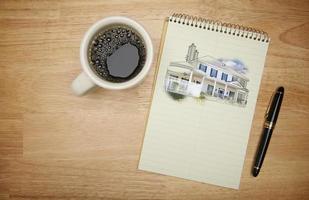 bloco de papel com desenho de casa, caneta e café foto