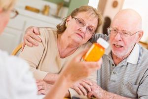 médico ou enfermeiro explicando medicamentos prescritos para casal adulto sênior foto