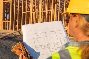 trabalhador da construção civil feminino com planos de casa no canteiro de obras foto