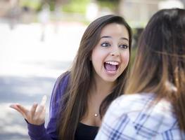 mulher jovem e expressiva de raça mista sentada e conversando com a namorada foto