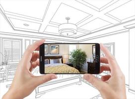 mãos segurando um smartphone exibindo a foto do quarto desenhando atrás