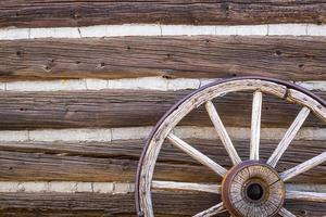 resumo da parede da cabana de madeira antiga vintage e roda de carroça. foto