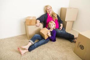 jovem mãe e filha no quarto vazio com caixas em movimento foto