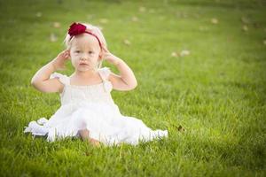 adorável menina usando vestido branco em um campo de grama foto
