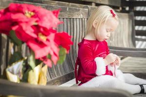 adorável menina sentada no banco com seu bastão de doces foto