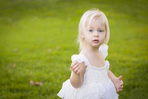 adorável menina usando vestido branco em um campo de grama foto