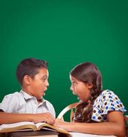 quadro de giz em branco atrás de menino hispânico e menina se divertindo estudando juntos foto