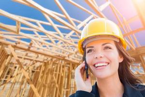 empreiteiro feminino no capacete usando telefone celular no canteiro de obras foto