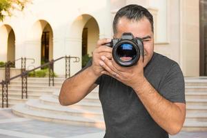 jovem fotógrafo masculino hispânico com câmera dslr ao ar livre foto