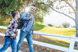 raça mista pai e filho caminhando ao ar livre com varas de pesca foto