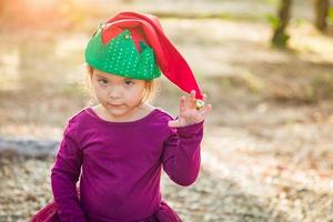 menina bonita de raça mista se divertindo usando chapéu de natal ao ar livre foto