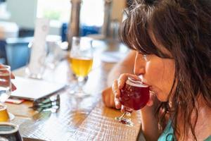 mulher bebendo copo de cerveja micro brew no bar com amigos foto