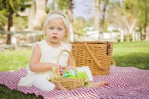 menina bonitinha curtindo seus ovos de páscoa na manta de piquenique foto