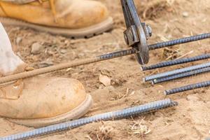 trabalhador cortando vergalhões de aço no canteiro de obras foto