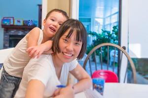 menino chinês e caucasiano de raça mista feliz se divertindo com a mãe chinesa dentro de casa foto