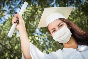 pós-graduação feminina em boné e vestido usando máscara facial médica foto